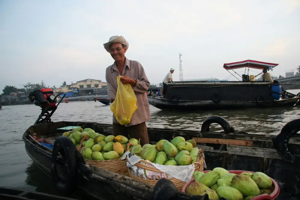 Boat vendor selling mangoes at a floating market in Can Tho
